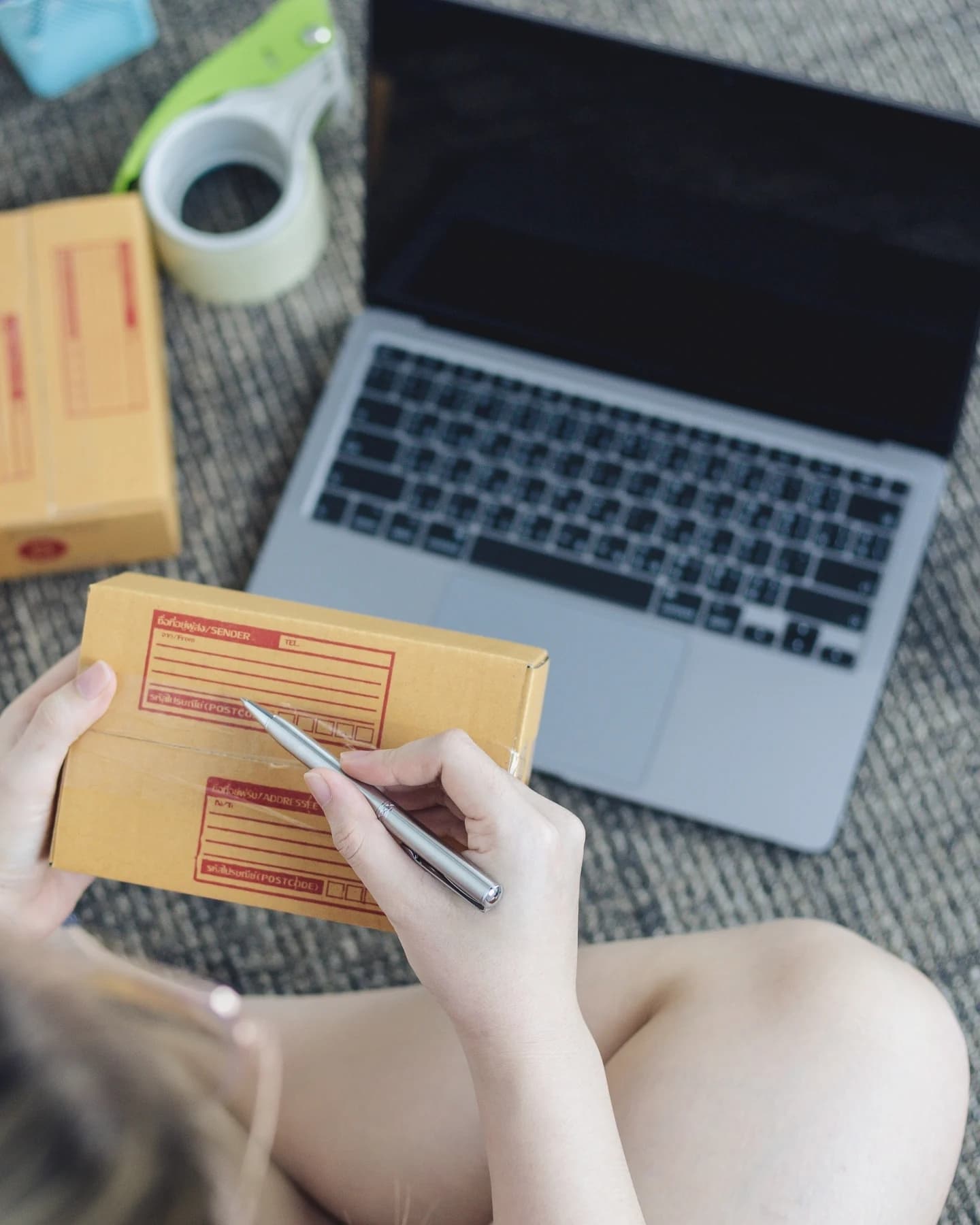 Writing a shipping label beside a laptop