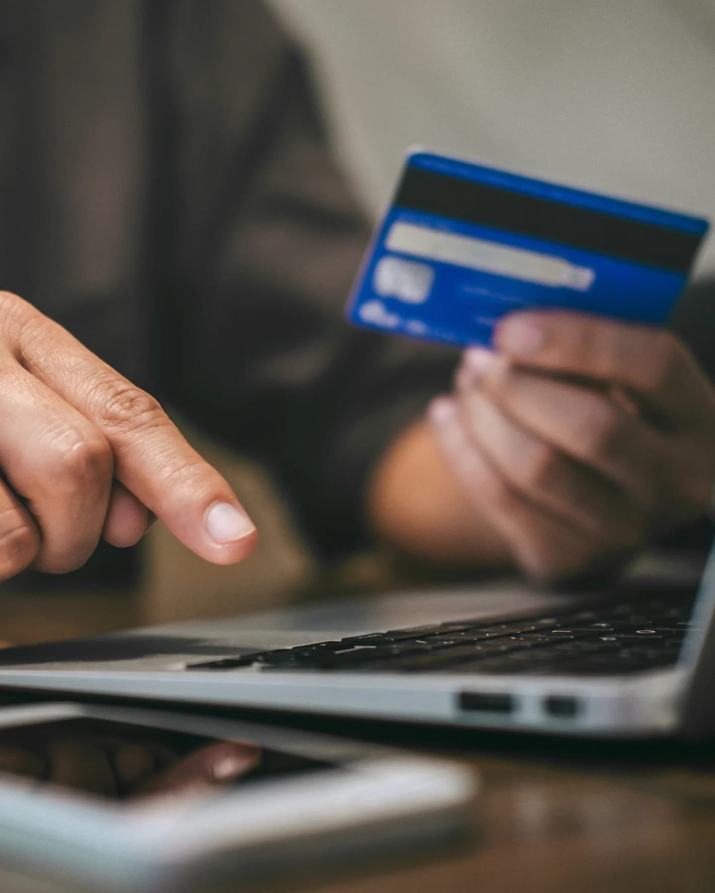 Holding a payment card while checking out on a laptop
