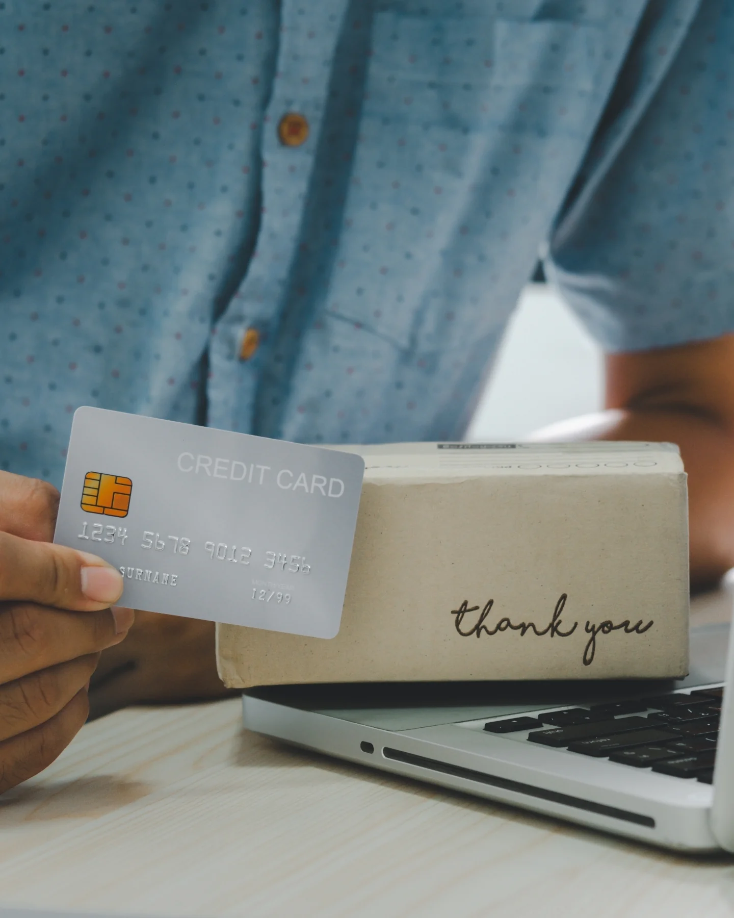 Payment card beside a packaged order and a laptop