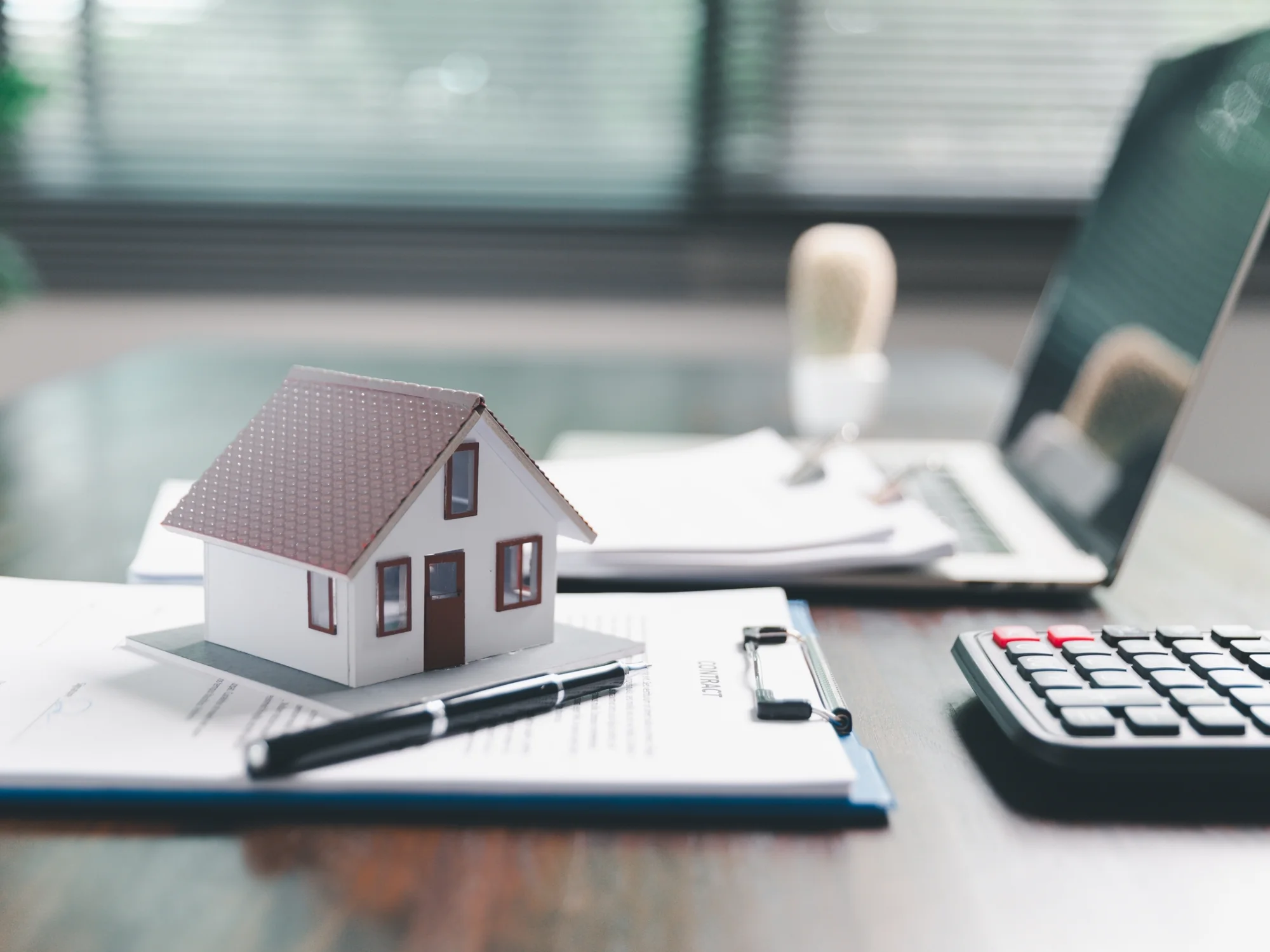 Model house, calculator and paperwork on a desk